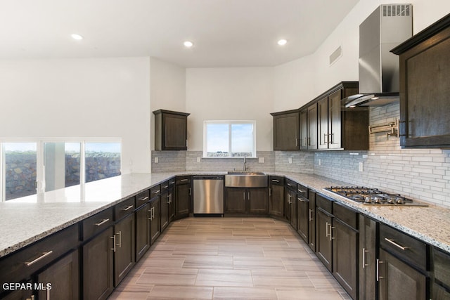 kitchen featuring wall chimney range hood, stainless steel appliances, backsplash, plenty of natural light, and sink