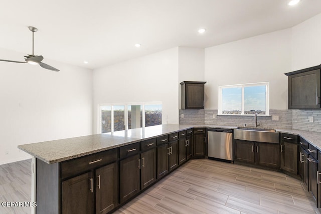 kitchen featuring stainless steel dishwasher, ceiling fan, backsplash, sink, and light stone countertops