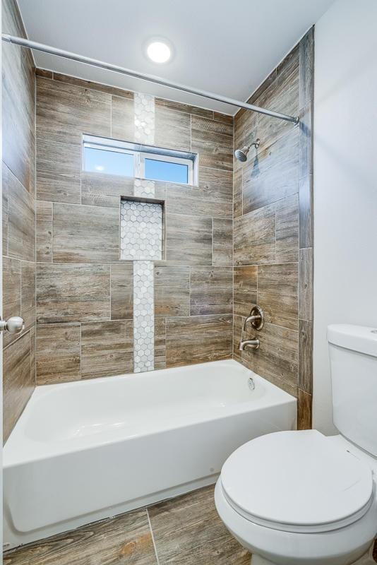 bathroom featuring tiled shower / bath combo and toilet