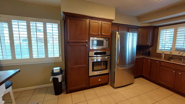 kitchen featuring appliances with stainless steel finishes, sink, plenty of natural light, and light tile floors