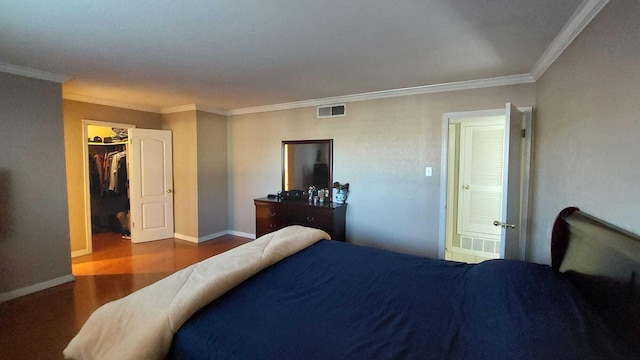 bedroom with a closet, ornamental molding, dark hardwood / wood-style floors, and a spacious closet