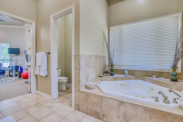 bathroom featuring a relaxing tiled bath, tile floors, crown molding, and toilet