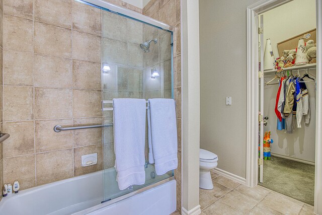 bathroom with shower / bath combination with glass door, toilet, and tile floors