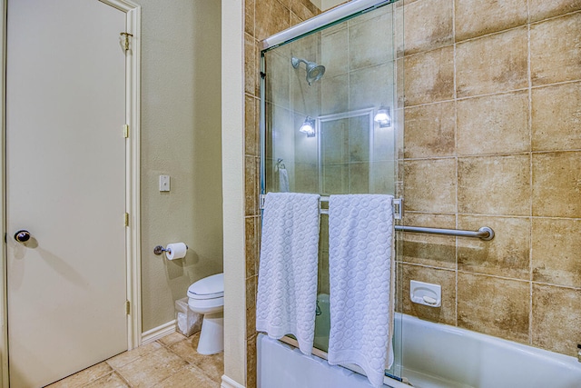 bathroom featuring toilet, tile flooring, and bath / shower combo with glass door