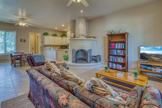 tiled living room with ceiling fan and a fireplace