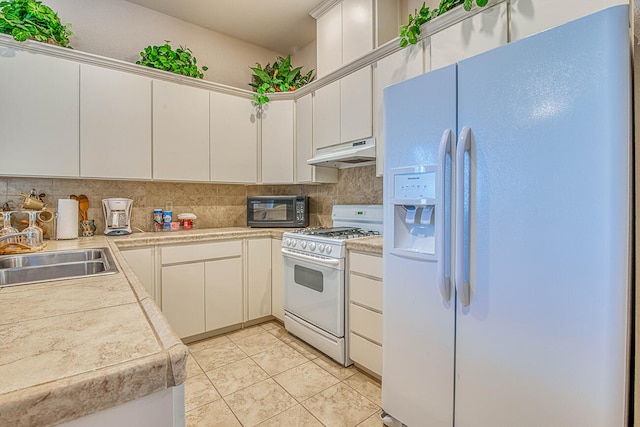 kitchen featuring white appliances, sink, light tile floors, white cabinets, and tasteful backsplash