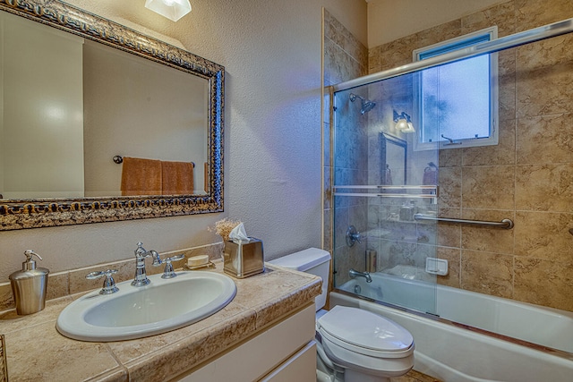 full bathroom featuring toilet, large vanity, and bath / shower combo with glass door