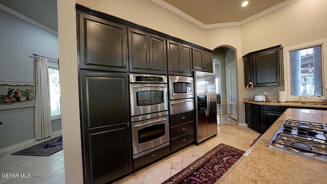 kitchen with light tile flooring, ornamental molding, appliances with stainless steel finishes, and sink