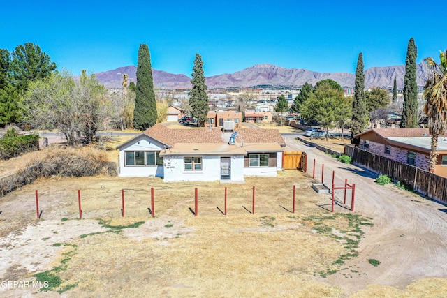 single story home featuring a mountain view, a front lawn, and fence