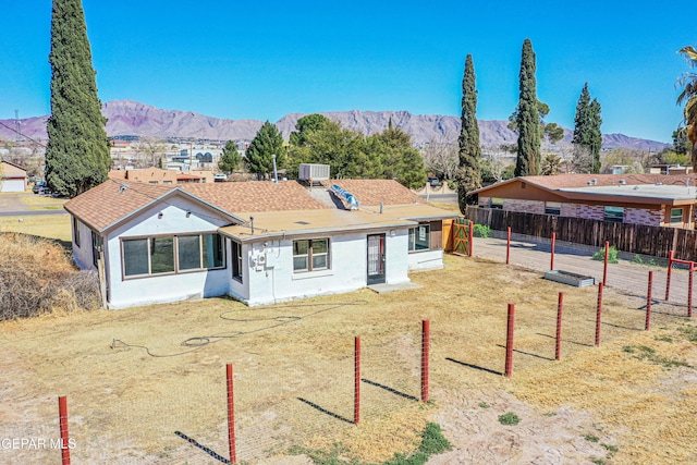 view of front of property with a mountain view, a shingled roof, cooling unit, and fence