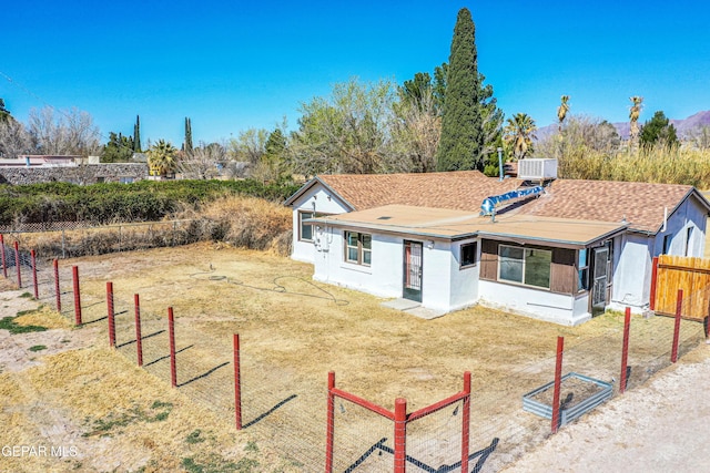 view of front of house featuring central AC unit, roof with shingles, and fence