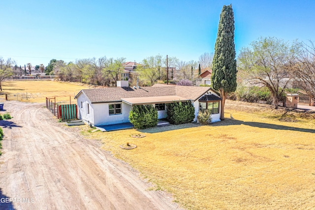 view of front facade featuring driveway, a front yard, and fence