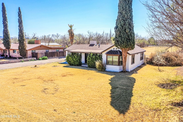 view of front of home featuring a front yard, fence, and stucco siding