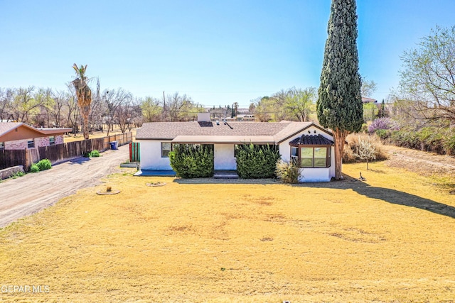 view of front of house with stucco siding, a front lawn, and fence