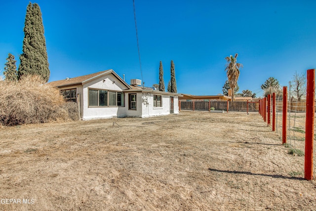 rear view of house with central air condition unit and fence