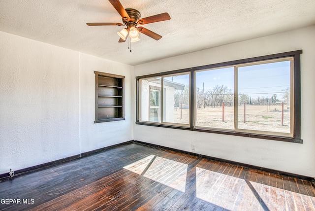 empty room featuring built in features, baseboards, hardwood / wood-style flooring, a textured ceiling, and a textured wall