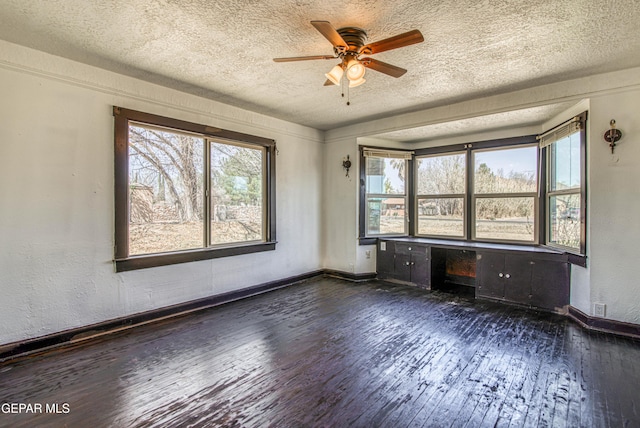 spare room with dark wood-type flooring, baseboards, and a textured ceiling