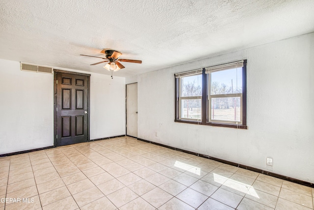 spare room with visible vents, baseboards, light tile patterned floors, a textured ceiling, and a ceiling fan