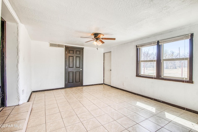 spare room featuring visible vents, baseboards, light tile patterned flooring, a textured ceiling, and a ceiling fan