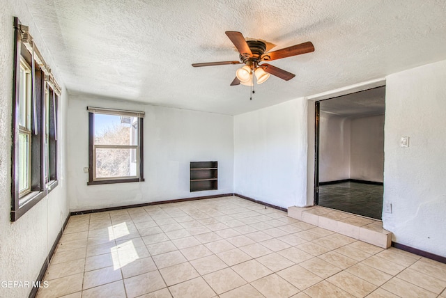 spare room featuring a textured ceiling, light tile patterned floors, and ceiling fan