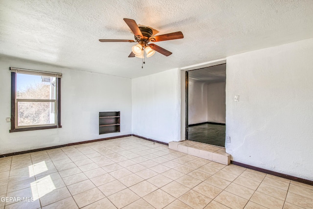 spare room featuring baseboards, a textured ceiling, and ceiling fan