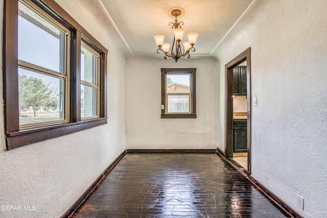 spare room with a wealth of natural light, crown molding, and a textured wall