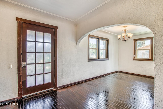 interior space with baseboards, ornamental molding, wood-type flooring, a textured wall, and a chandelier