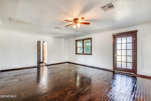 spare room with hardwood / wood-style floors, arched walkways, and visible vents