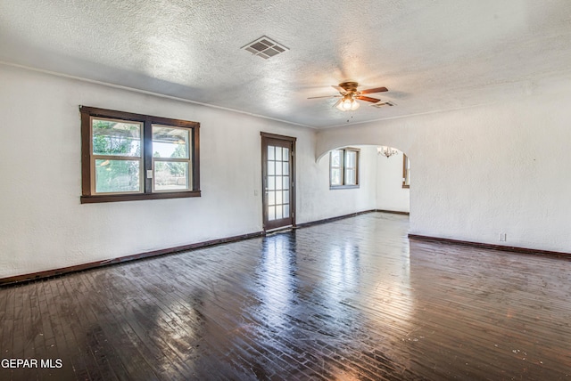 spare room featuring a wealth of natural light, visible vents, arched walkways, and hardwood / wood-style floors