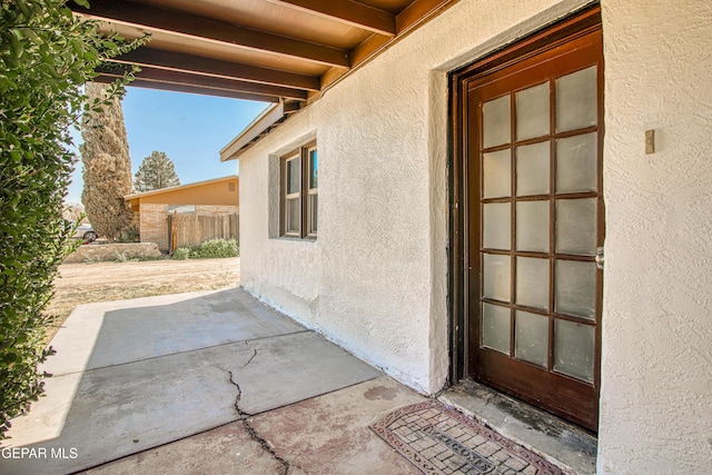 property entrance with stucco siding and a patio area