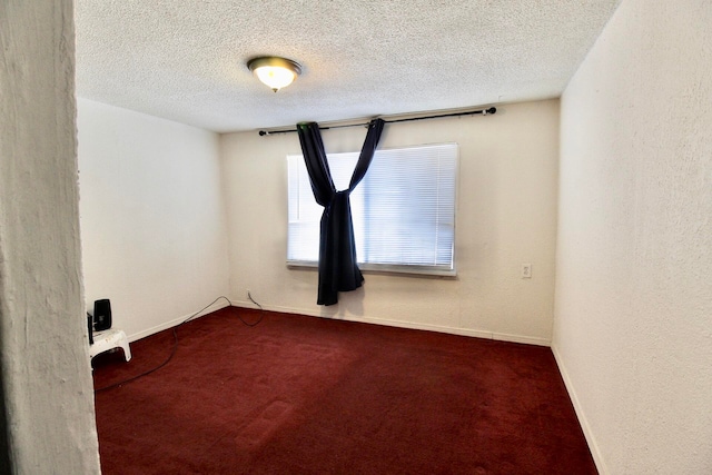 empty room featuring a textured ceiling and dark colored carpet