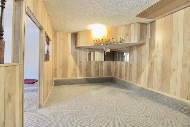 interior space with carpet, wooden walls, bar area, and a textured ceiling