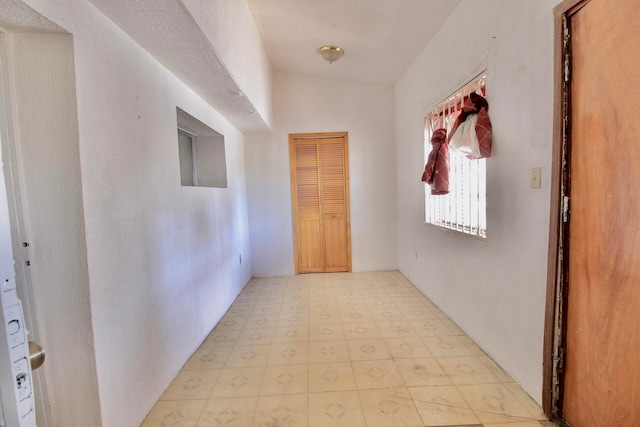 hall featuring lofted ceiling and light tile flooring