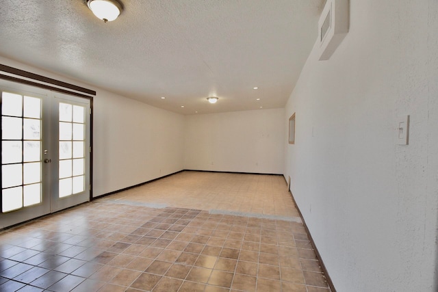 unfurnished room featuring light tile floors, a textured ceiling, and french doors