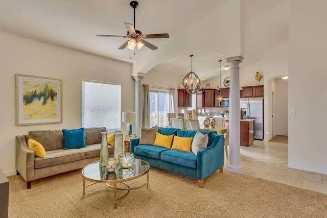 tiled living room featuring ornate columns, high vaulted ceiling, and ceiling fan with notable chandelier