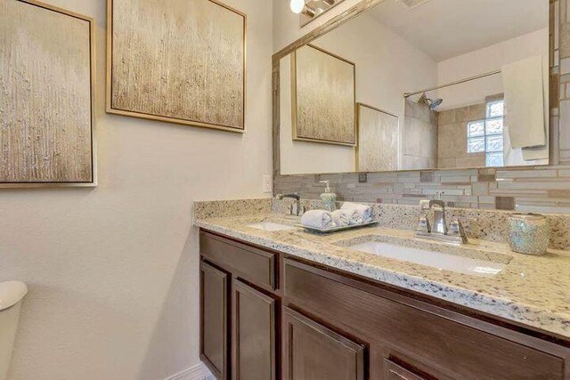 bathroom featuring oversized vanity, toilet, and double sink