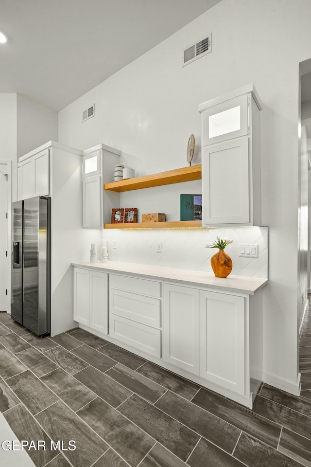 kitchen with white cabinets, stainless steel refrigerator with ice dispenser, and light countertops