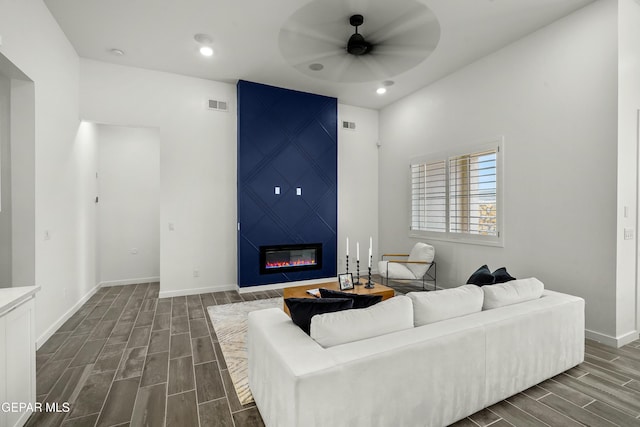 living room with wood tiled floor, a fireplace, visible vents, and baseboards