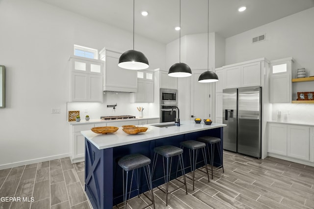 kitchen featuring light countertops, appliances with stainless steel finishes, glass insert cabinets, white cabinets, and a sink