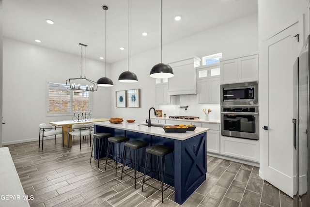 kitchen with white cabinetry, stainless steel appliances, light countertops, and decorative light fixtures