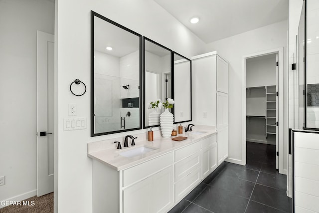 full bathroom with double vanity, a shower stall, a spacious closet, and a sink