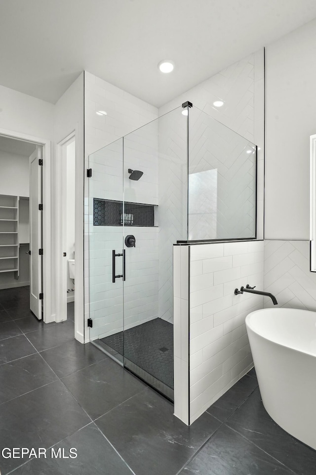 bathroom featuring a stall shower, a freestanding tub, tile walls, and tile patterned floors