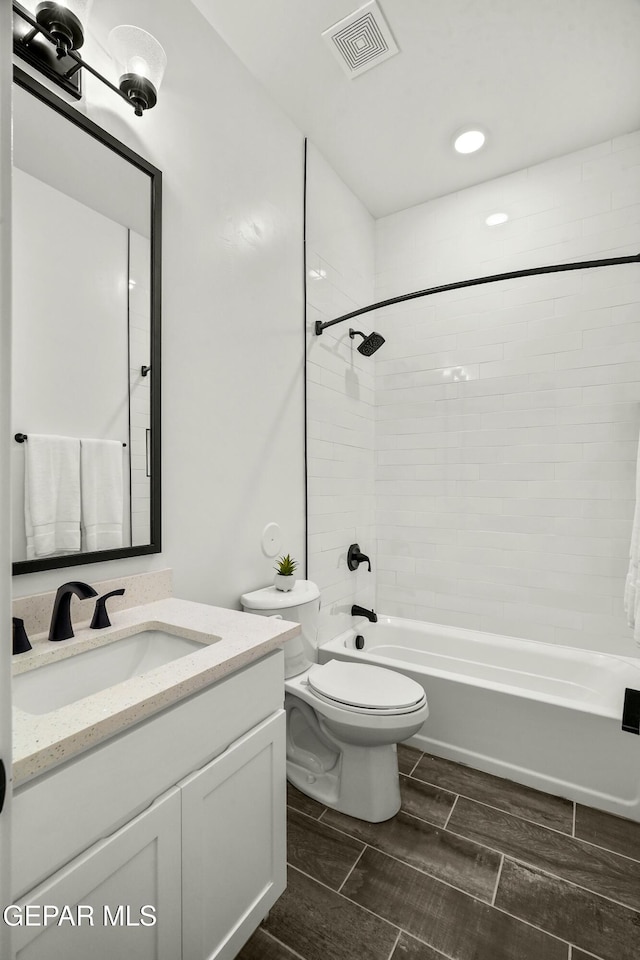 bathroom featuring wood finish floors, visible vents, toilet, tub / shower combination, and vanity