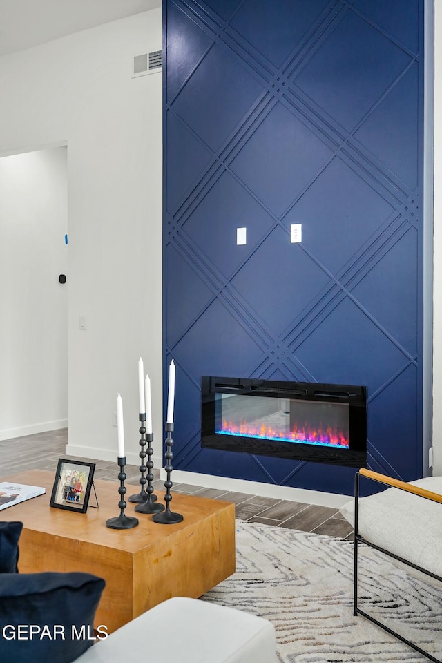 details with a glass covered fireplace, visible vents, baseboards, and wood finished floors