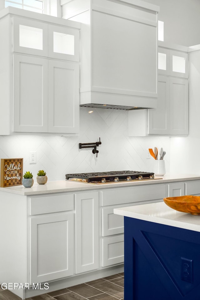 kitchen with backsplash, glass insert cabinets, white cabinets, and light countertops