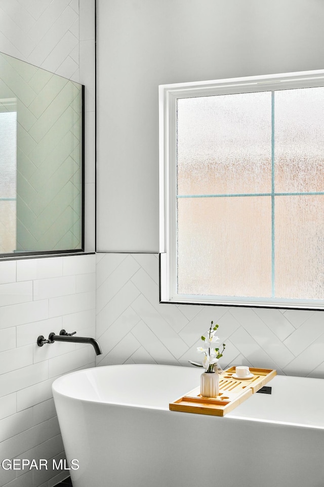 bathroom with plenty of natural light, tile walls, and a freestanding bath