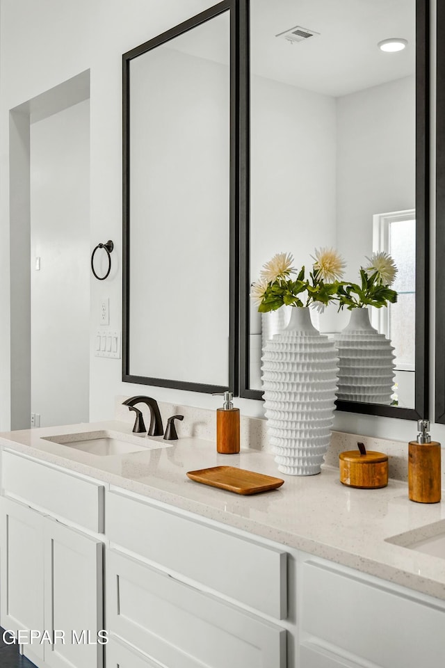 bathroom with double vanity, visible vents, and a sink