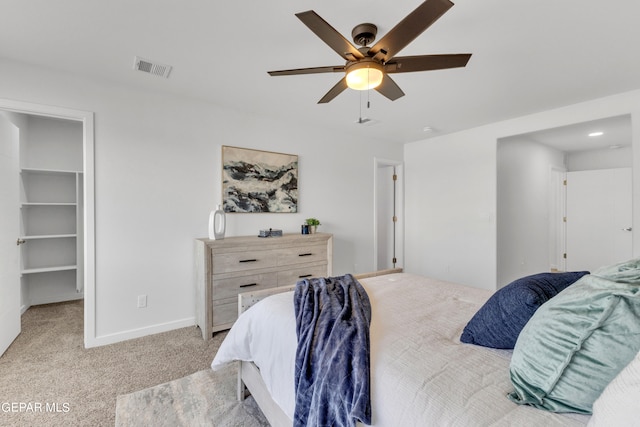 bedroom featuring a closet, a spacious closet, ceiling fan, and light colored carpet