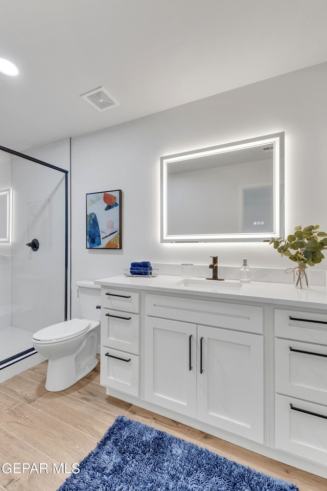 bathroom featuring toilet, a shower with door, hardwood / wood-style floors, and vanity