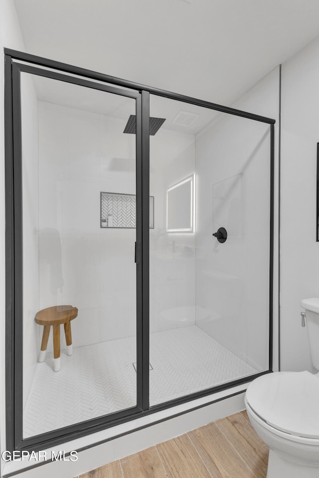 bathroom featuring an enclosed shower, toilet, and hardwood / wood-style floors